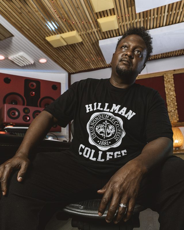 Artist in a Hillman College shirt seated in the studio during the Seasons Shift event