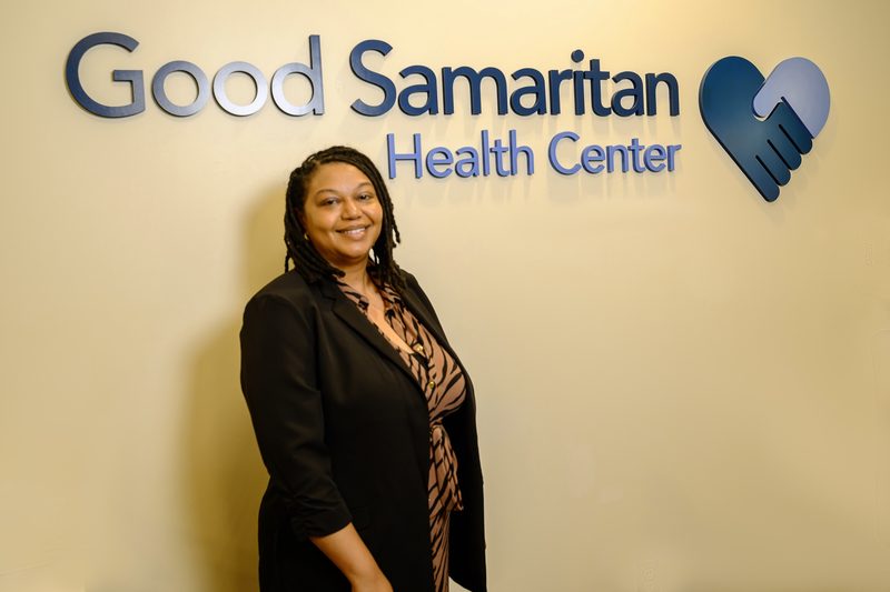 Shameka Allen, CEO, beside the Good Samaritan Health Centers of Gwinnett logo wall
