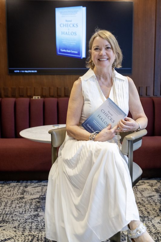Cynthia Currence holding her book Beyond Checks and Halos