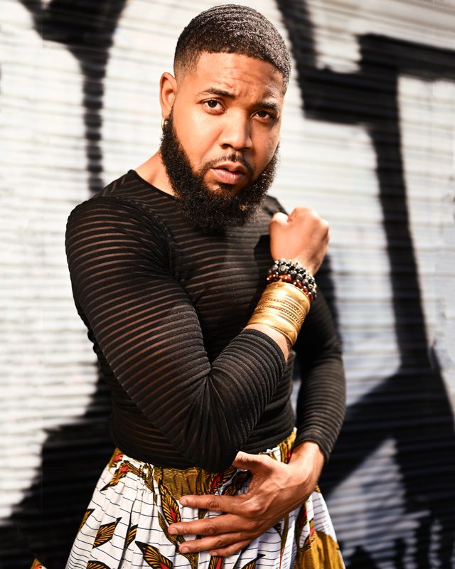 Justin Riley in a menswear look against street graffiti