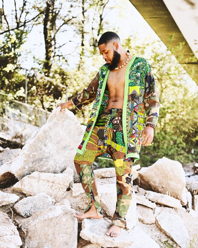 Justin Riley in a menswear look against street graffiti