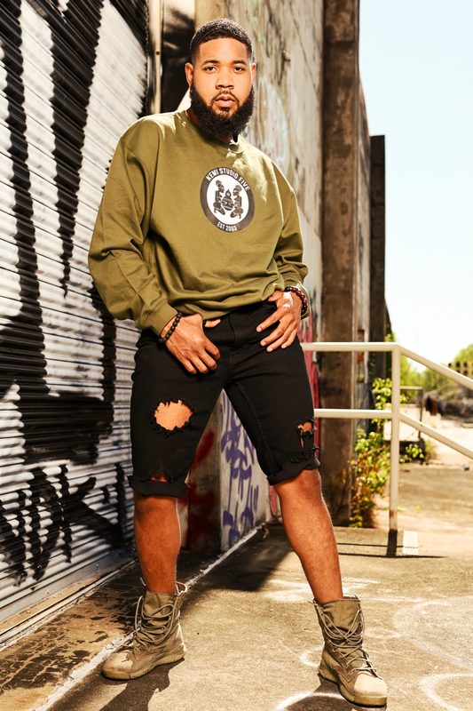 Justin Riley in a menswear look against street graffiti