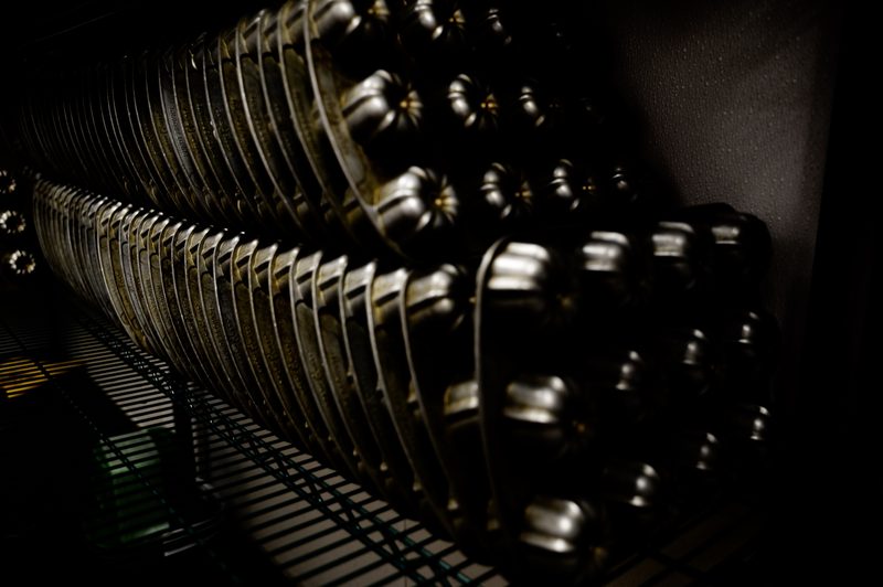 Rows of bundt cake pans in low light behind the counter